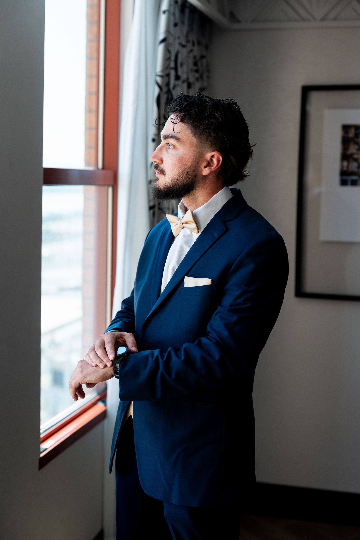 Person in a navy suit gazing out a bright window
